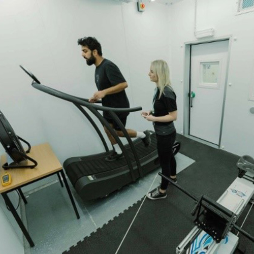 A participant on a treadmill while a Human Performance Specialist looks on